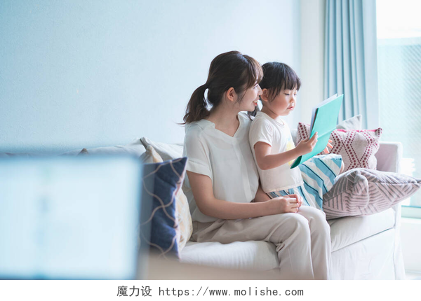 母亲和女儿坐在沙发上看画册母亲和女儿坐在沙发上看画册